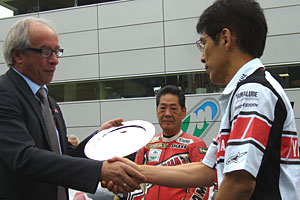 FIMの役員から、WGP参戦50周年記念を表彰する楯を授かる北川さんは、WGP50th活動事務局長でもあった。 FIMの役員から、WGP参戦50周年記念を表彰する楯を授かる北川さんは、WGP50th活動事務局長でもあった。
